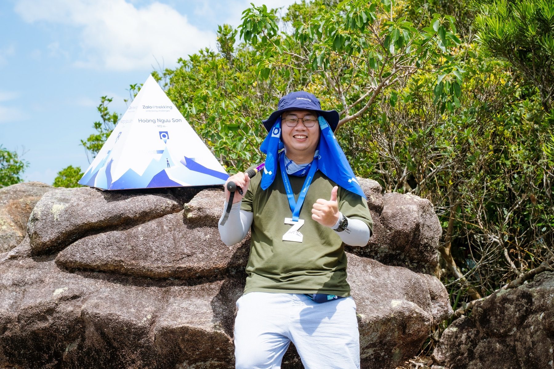 Nguyen Le Phong smiling at the Hoang Nguu Son summit marker after a trekking route