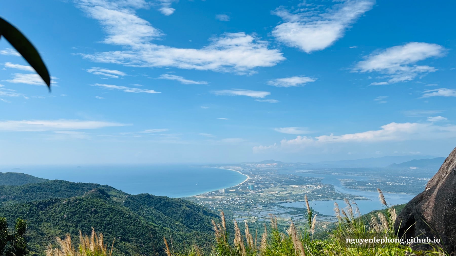 Tầm nhìn từ Hoàng Ngưu Sơn qua các lớp sườn núi xanh, vịnh biển cong và đường bờ Nha Trang dưới trời xanh sáng