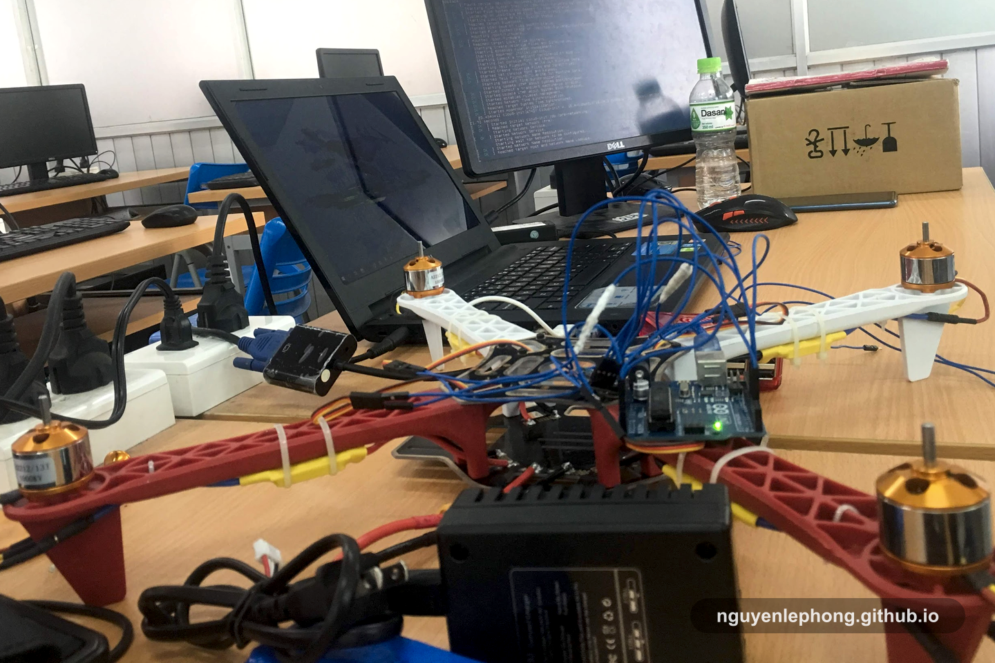Cận cảnh một drone prototype, dây nối, laptop và bàn làm việc, phần hạ tầng âm thầm gánh kết quả nhìn thấy được từ rất lâu trước lúc trình bày.