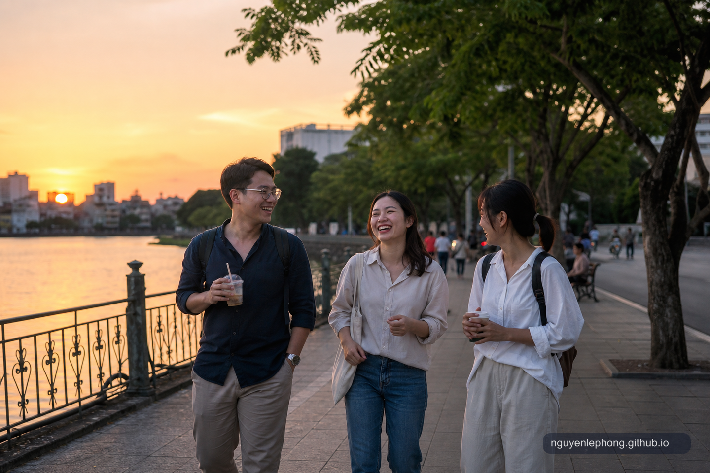Three Vietnamese friends walk beside a river at sunset, laughing together after work with simple drinks in hand.