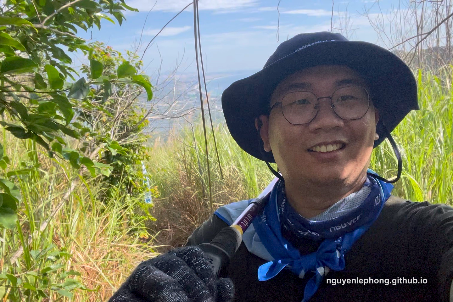 Nguyen Le Phong smiles midclimb on a trail with the coast behind him, a quieter moment between hard stretches.