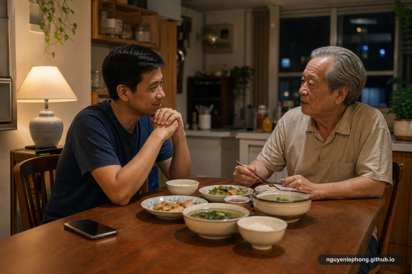 An adult son shares a quiet dinner with his older father in a warm home kitchen while a phone rests unused on the table.