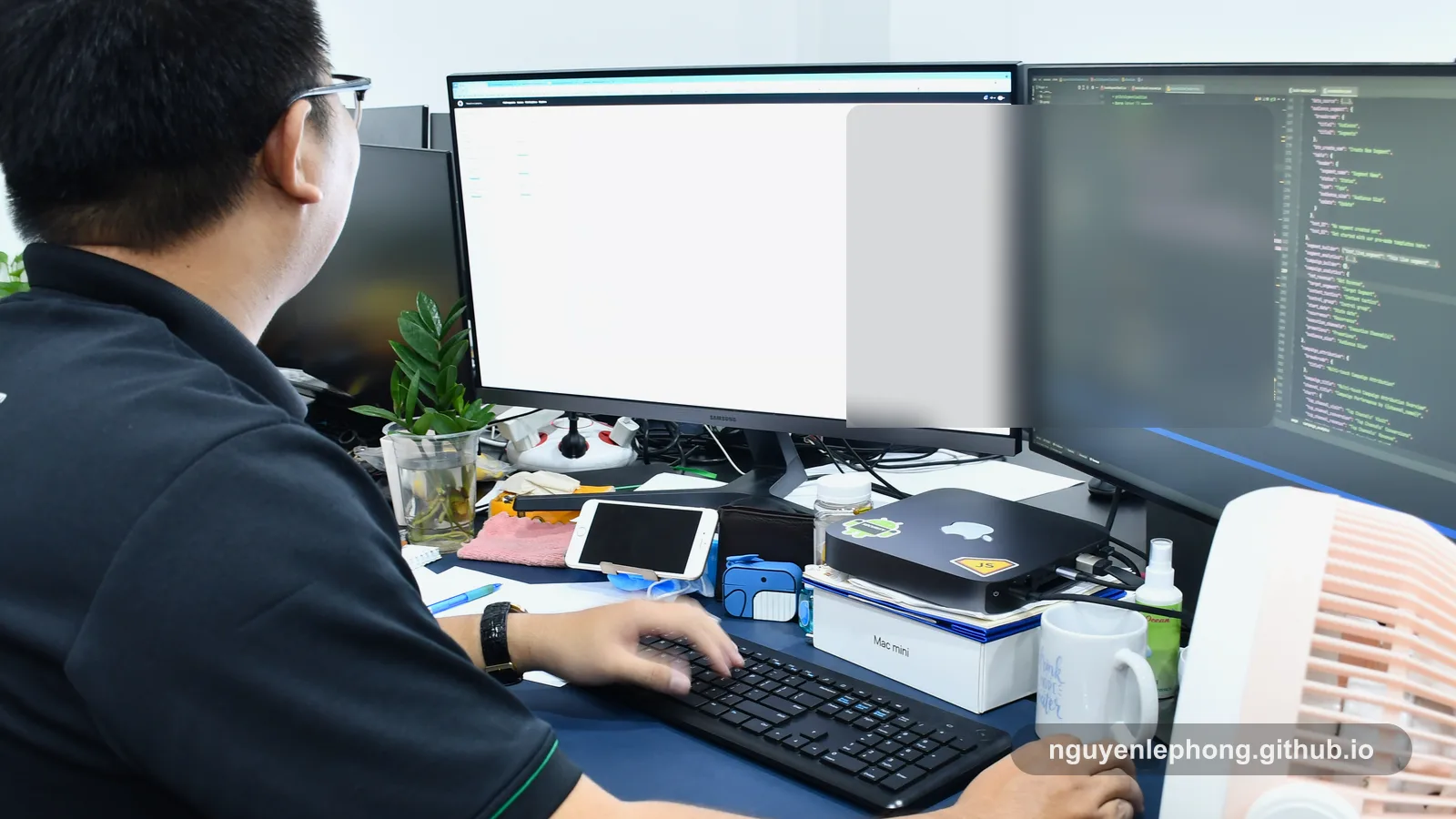 Nguyen Le Phong làm việc trước bàn hai màn hình, xem lại code và chi tiết triển khai trong một văn phòng chung.