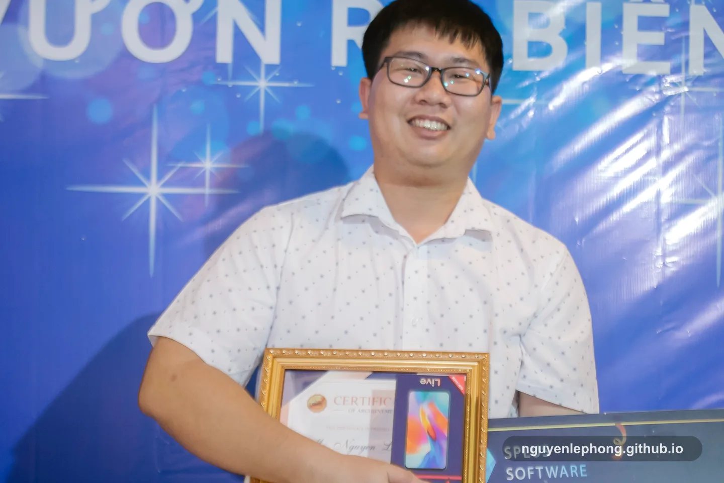 Nguyen Le Phong smiles with a framed certificate and award board at a recognition event, showing the visible outcome people usually notice.