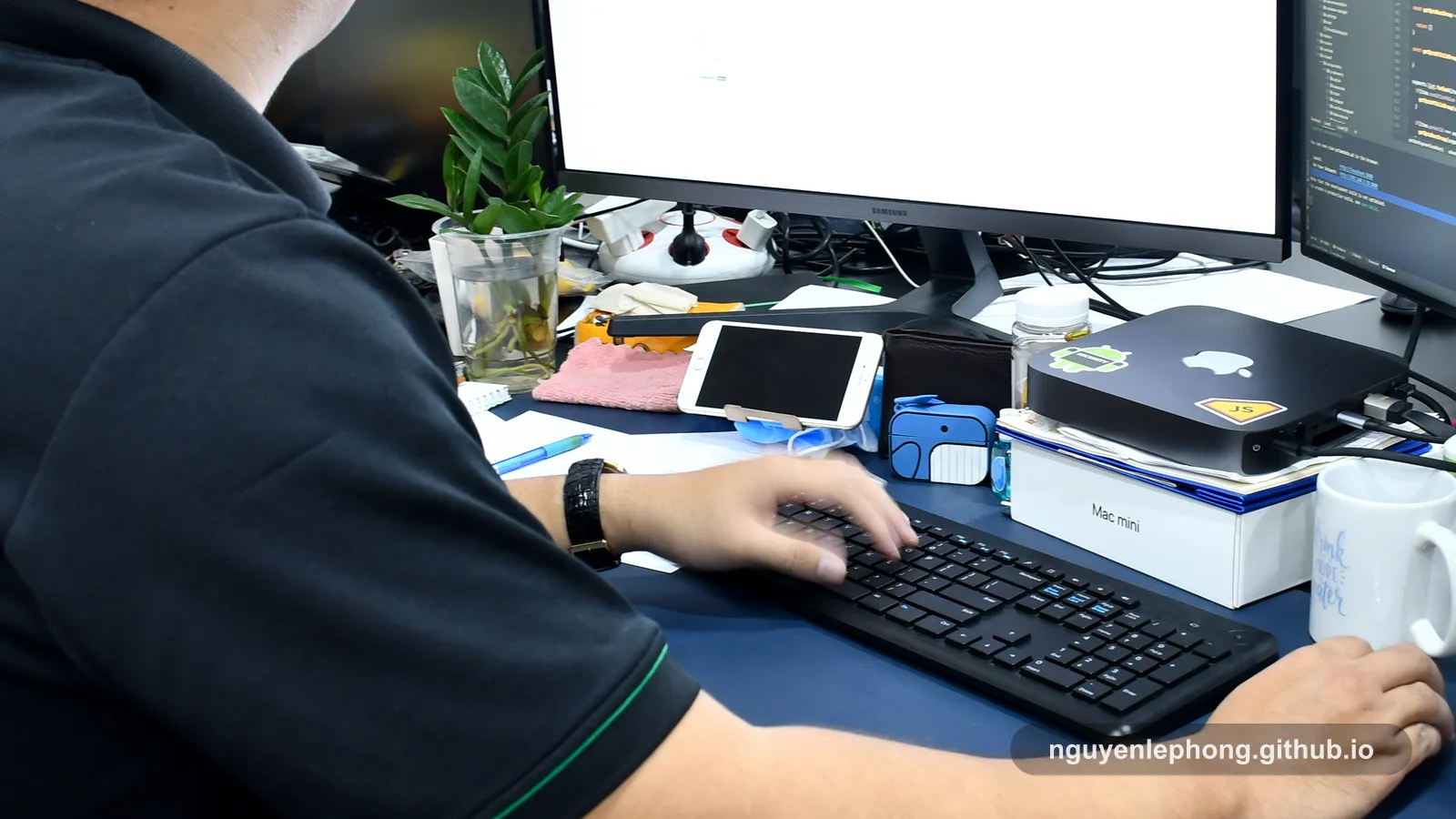 Nguyen Le Phong works quietly at a crowded desk with monitors, notes, and tools, turning steady support into deeper operational capability.