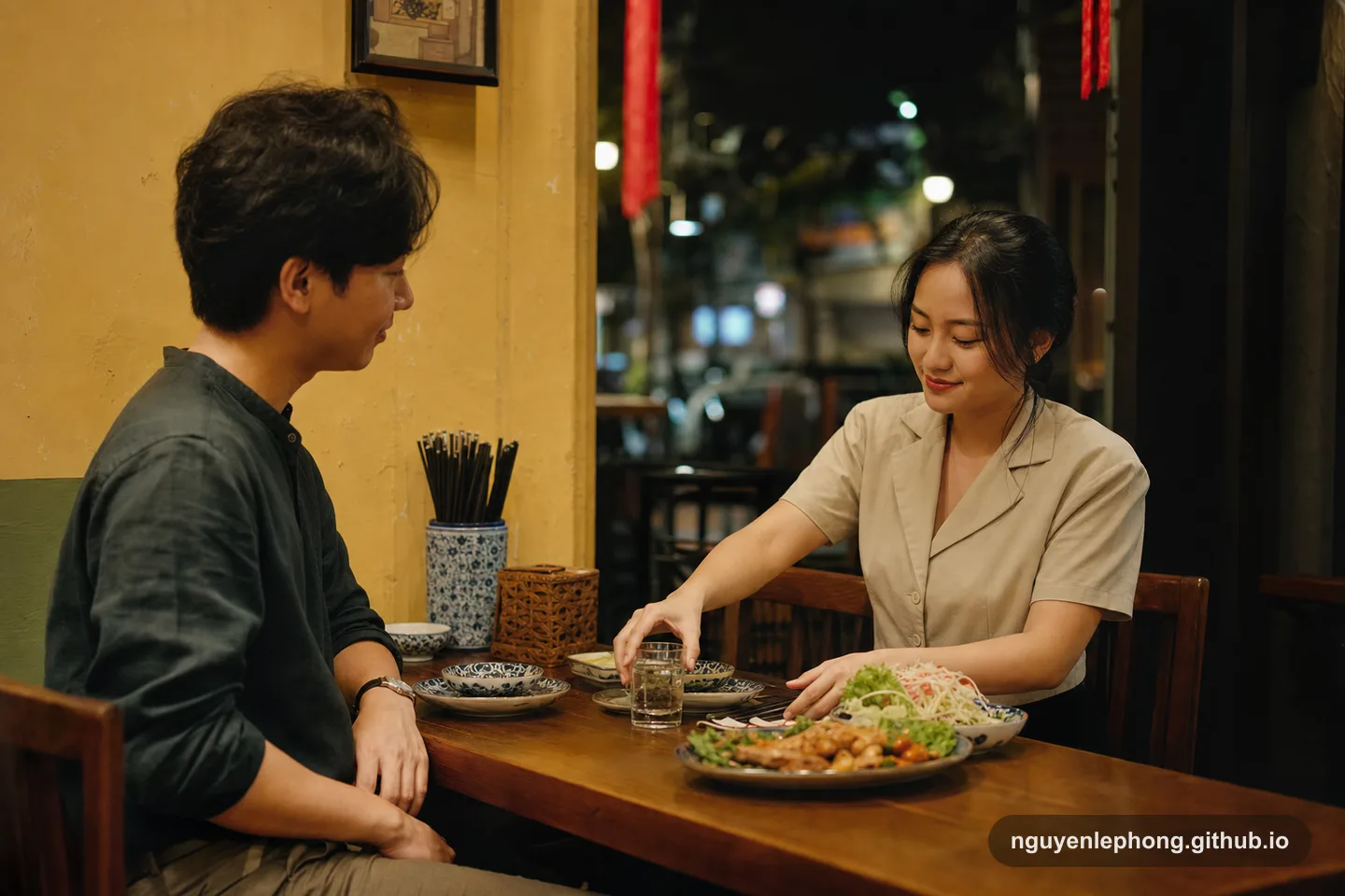 At a quiet Vietnamese restaurant, one person gently straightens the table setting and slides a glass of water closer before the meal begins, revealing care through a small everyday gesture.