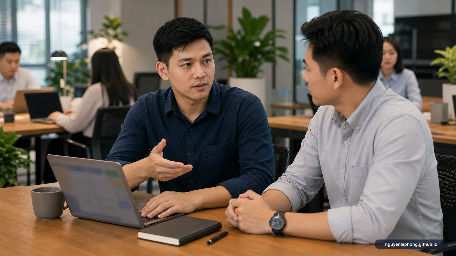 A young Vietnamese professional calmly walks a teammate through the next step on an unclear task while the rest of the office keeps moving around them.